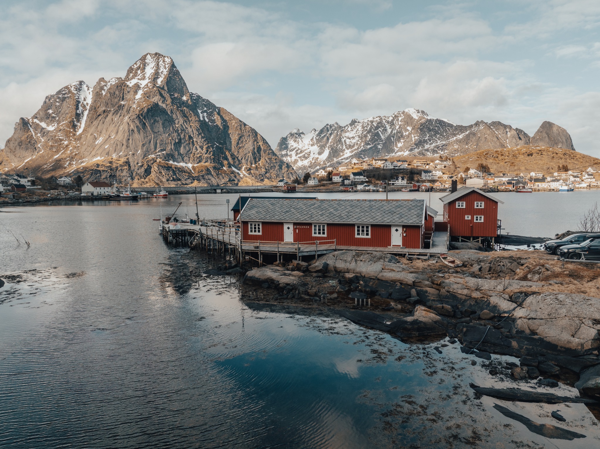 Draugen Rorbu ved vannet med fjell i bakgrunnen