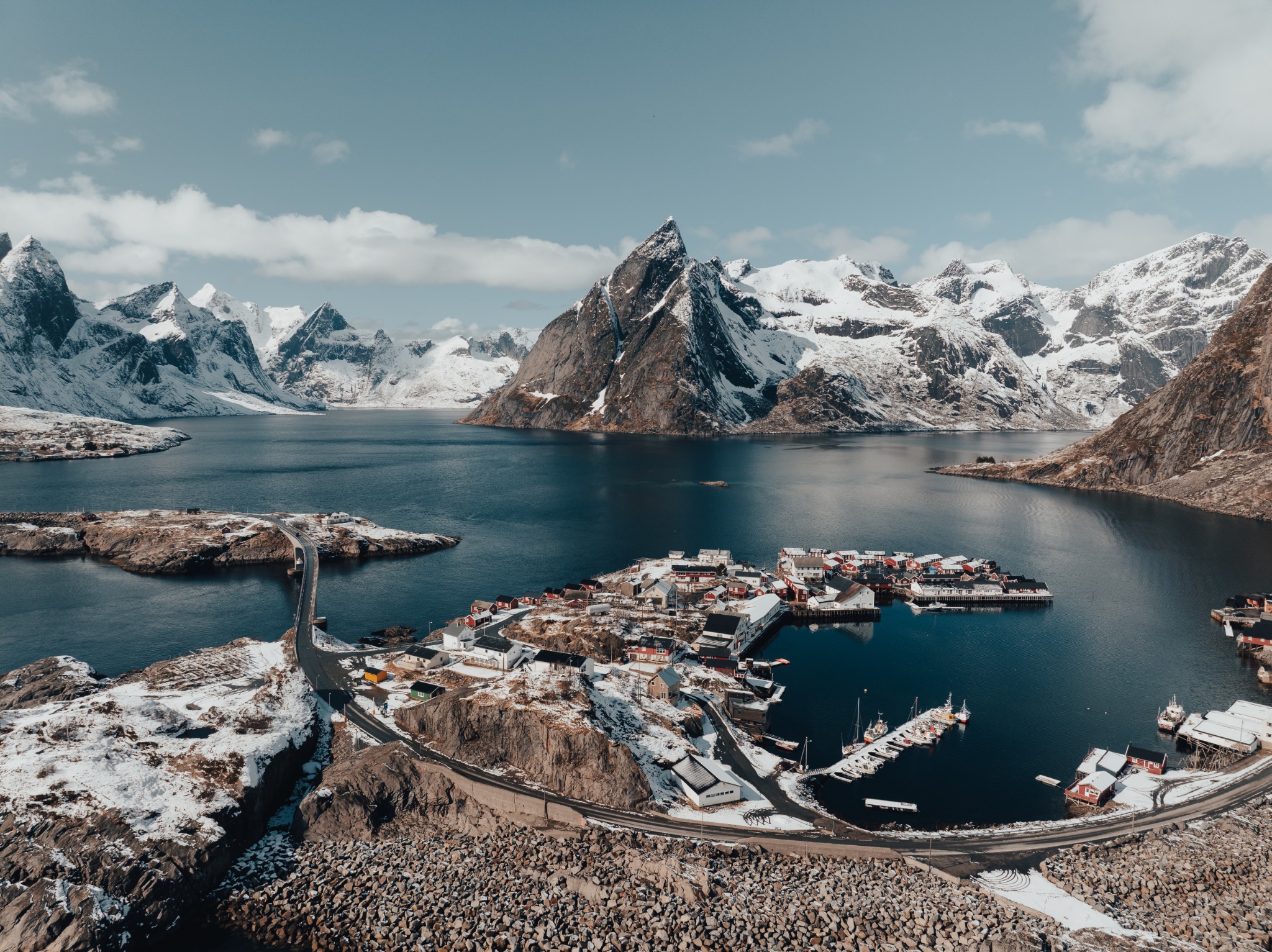 Flyfoto av Hamnøy med havn, fjord og snødekte fjell