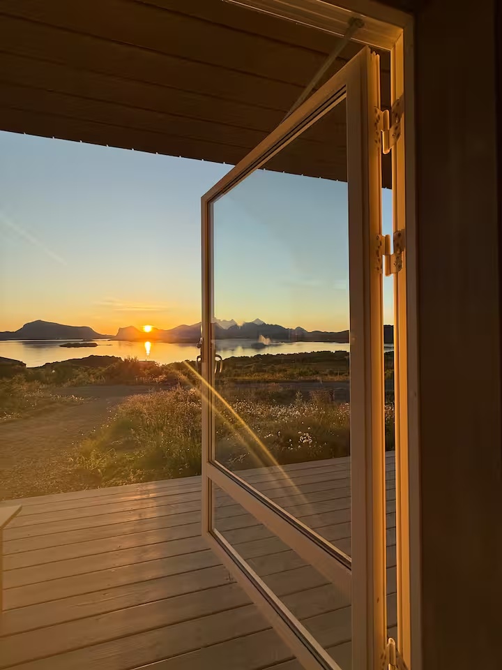 Solnedgang over hav og fjell sett fra terrassen ved Lofoten Holidays