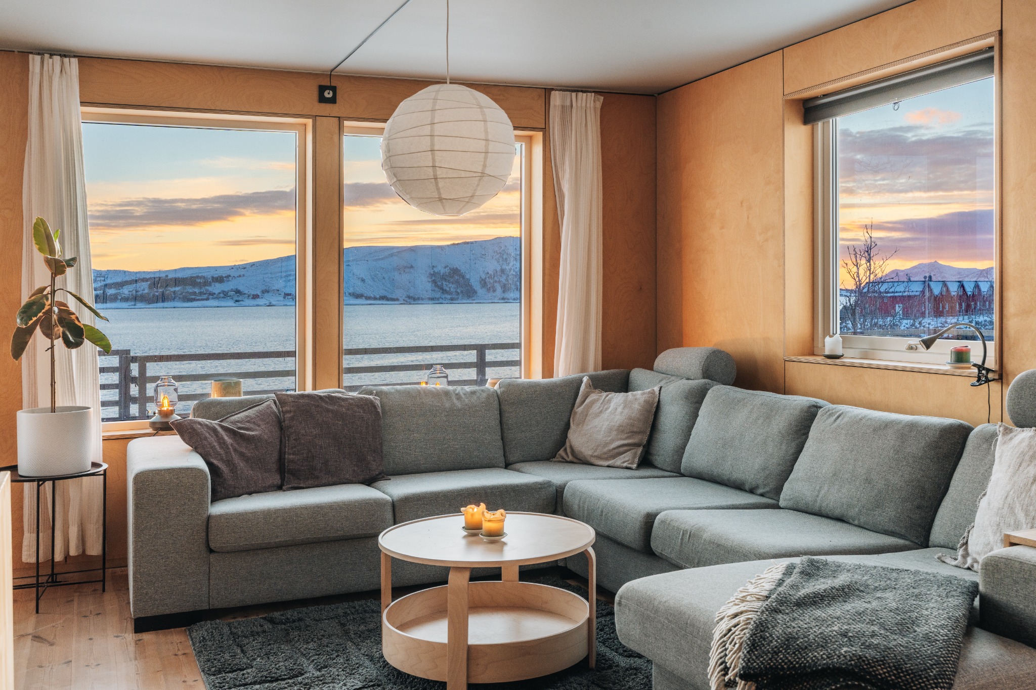 Stue i Lofoten Seaside Villa med store vinduer og utsikt mot havet og fjellene