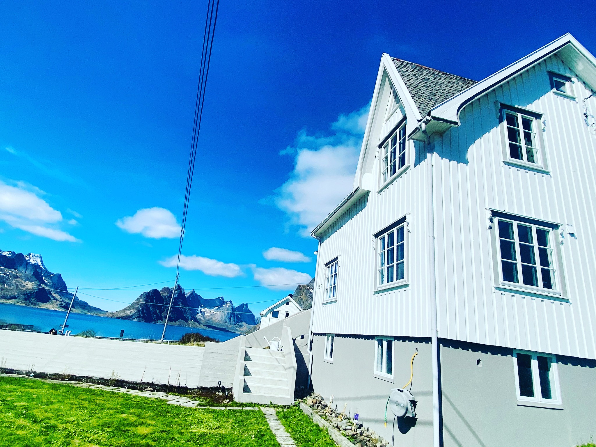 Reinehuset med hvit trefasade og utsikt mot hav og fjell