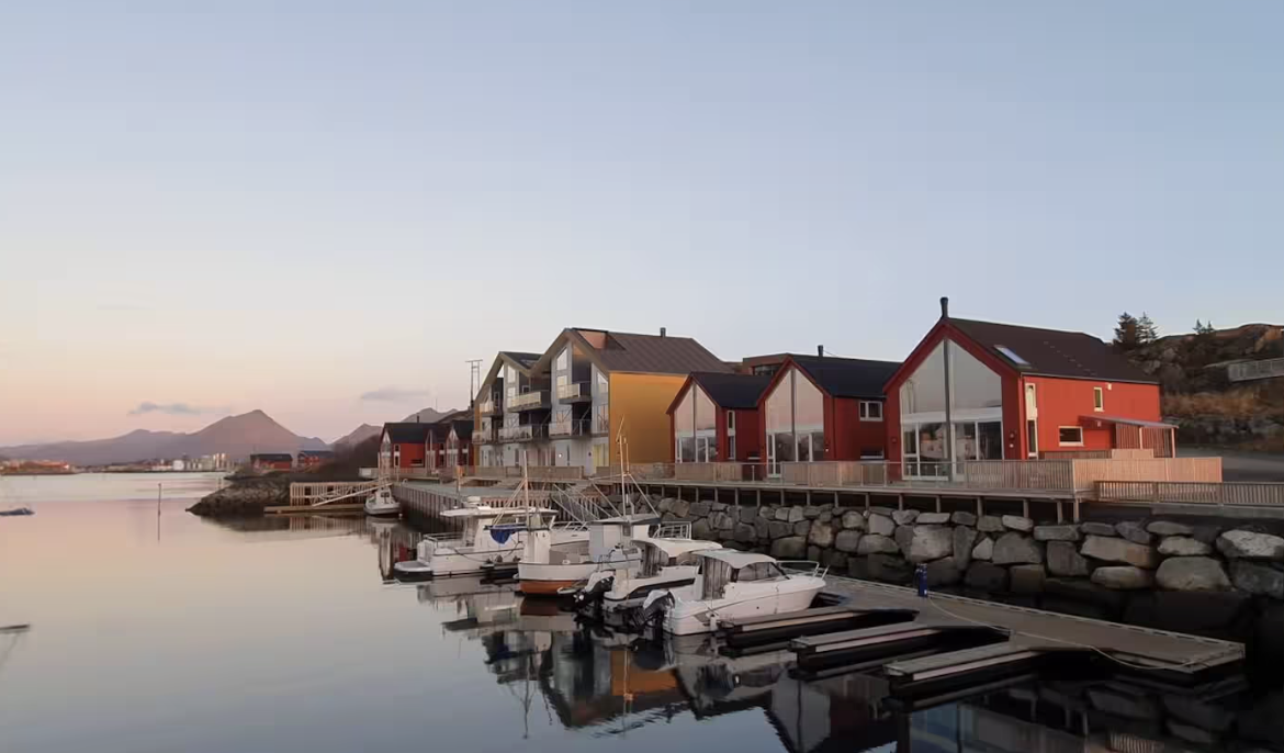 Rorbuer ved vannkanten og båter i havnen på Ballstad